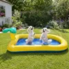 To små hvide hunde leger i Active Canis Pet Splash Pool i en solrig have, mens tynde vandstråler sprøjter ind fra siderne og giver sjov afkøling på varme dage